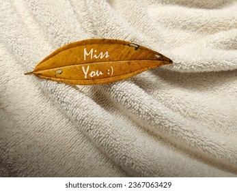Yellowish leaf on white towel. Minimalist background with warm hue color theme. - Shutterstock ID 2367063429