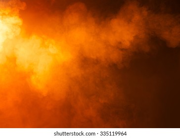 Yellow/Orange mysterious fog photographed on a black background. Ideas as a background texture or overlay. Bright light coming from the left of the image. 