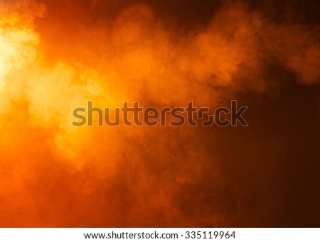 Yellow/Orange mysterious fog photographed on a black background. Ideas as a background texture or overlay. Bright light coming from the left of the image. 