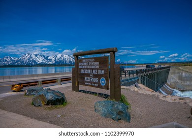 YELLOWSTONE, MONTANA, USA MAY 24, 2018: Informative Sign In Jackson Lake Dam Built In 1911 In Grand Teton National Park, Has Enlarged The Natural Lake That Is Primarily Fed By The Snake River