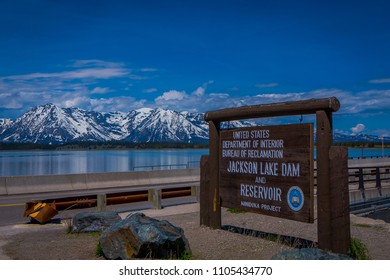 YELLOWSTONE, MONTANA, USA MAY 24, 2018: Informative Sign In Jackson Lake Dam Built In 1911 In Grand Teton National Park, Has Enlarged The Natural Lake That Is Primarily Fed By The Snake River