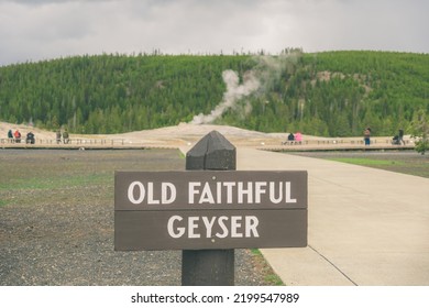 Yellowstone Old Faithful Geyser Sign With Geyser Steaming In The Background Close Shot Moody Sky