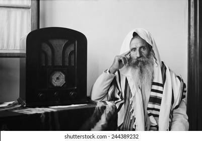 Yemenite Rabbi, in traditional robes and prayer shawl, listening to radio, ca. 1937.