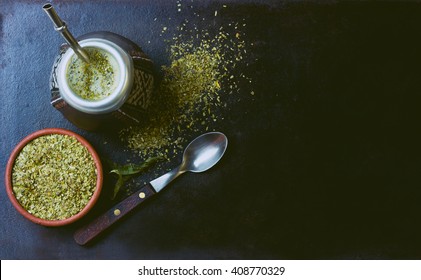 Yerba mate in calabash and dry herb in clay bowl on black background. Top view