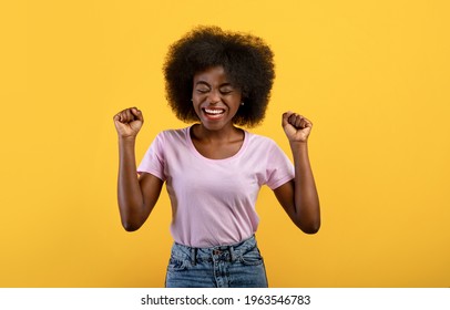 Yes, Achievement Concept. Overjoyed Black Woman Cheering And Screaming, Celebrating Victory On Yellow Studio Background. Emotional Overwhelmed Lady Yelling And Shaking Clenched Fists