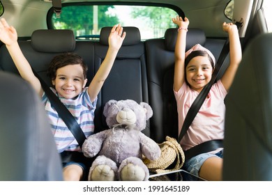 Yes! Cheerful little siblings sitting in the car while celebrating and feeling happy for an exciting family trip outside 