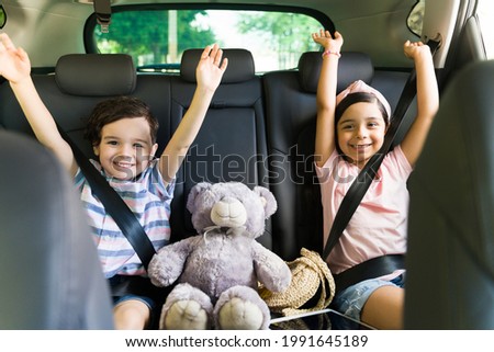 Yes! Cheerful little siblings sitting in the car while celebrating and feeling happy for an exciting family trip outside 