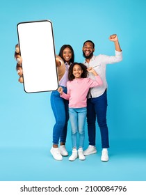 Yes. Excited Black Family Holding Big Smartphone With Empty White Screen In Hand, Shaking Clenched Fists, Cheerful Guy, Lady And Girl Celebrating Win, Blue Wall, Mock Up Collage, Full Body Length