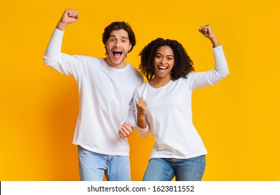 Yes. Overjoyed interracial couple celebrating success with raised fists, posing together over yellow background with empty space - Powered by Shutterstock