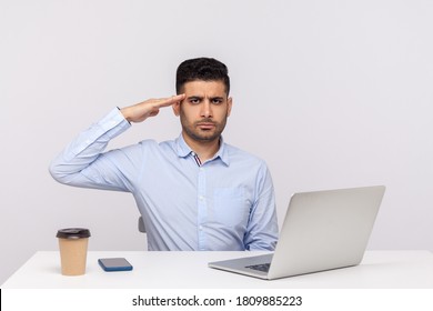 Yes sir! Responsible man employee sitting office workplace with laptop on desk, looking at camera with salute and ready to do your order, following discipline. studio shot isolated on white background