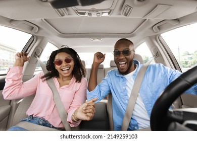 Yes, Summer Vacation Concept. Portrait of excited playful black couple in sunglasses driving car, shaking fists dancing to music enjoying favorite playlist, resting on weekend, windshield view - Powered by Shutterstock