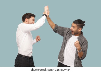 Yes We Did. Expression Profile Side View Of Two Young Handsome Happy Satisfied Bearded Partner Celebrating Triumph Together, Giving Hi Five Hands. Indoor Studio Shot, Isolated On Light Blue Background