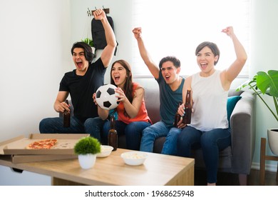 Yes, We Are Winning! Cheerful College Friends Watching A Sports Game On The Tv While Celebrating And Cheering In The Living Room After Their Favorite Soccer Team Won