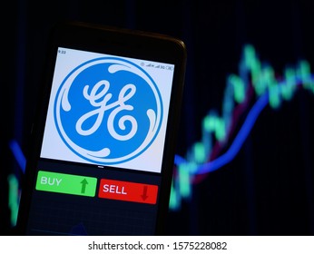 YESSENTUKI, RUSSIA - November 29, 2019: Company Logo General Electric Company On Smartphone Screen, Hand Of Trader Holding Mobile Phone Showing BUY Or SELL On Background Of Stock Chart