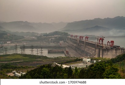 Yichang, China - May 6, 2010: Yangtze River, 3-Gorges Dam. Foggy smog morning,  Wide shot on down-river side long shot over the dam with its red cranes to handle gate plugs. Mountains on horizon.