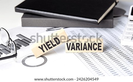 YIELD VARIANCE - text on wooden block with chart and notebook