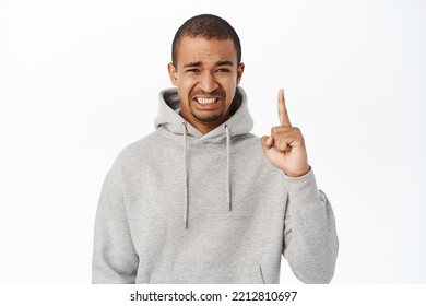 Yikes. Guy Points Up And Squinting Face, Smth Painful Or Sour, Stands Over White Background