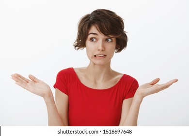 Yikes how embarrassing sorry. Awkward cute silly attractive woman short haircut grimacing perplexed unsure have doubts shrugging hands spread sideways unaware puzzled answer stand white background