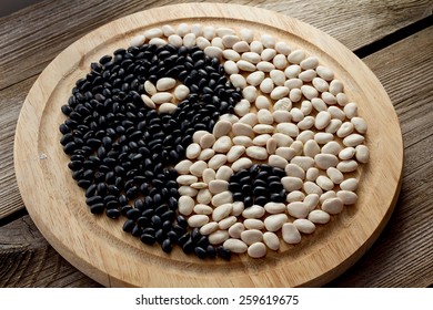 Yin And Yang Of Black And White Beans On Wooden Plate