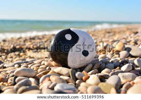 yin yang symbol painted on a rock on the sea beach on a sunny day