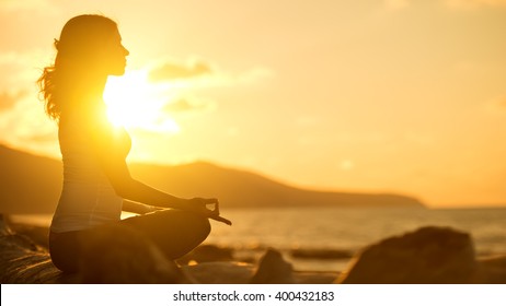 yoga in the beach. woman meditating in lotus pose at sunset - Powered by Shutterstock