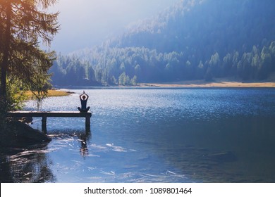 Yoga Beautiful Background, Harmony In Life, Meditation Practice, Silhouette Of Woman Sitting In Lotus Position On The Pier Of Lake And Doing Breathing Exercises In Beautiful Landscape