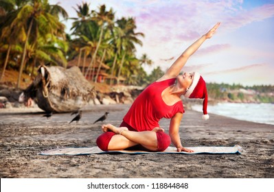 Yoga by young woman in red costume and red christmas hat on the beach near the ocean at tropic background in India - Powered by Shutterstock