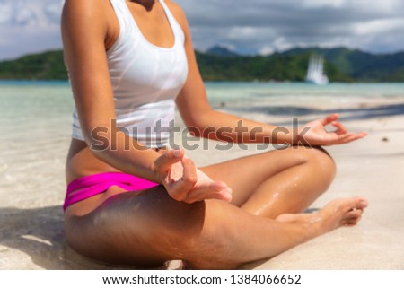 Yoga class on beach woman meditating lotus pose with hands in mudra position for concentration and energy. Health and wellness.
