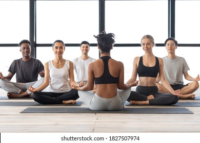 Yoga Class. Smiling Multiethnic Men And Woman Having Group Lesson With Black Female Instructor, Meditating Together In Lotus Position, Sitting On Mats In Modern Loft Studio, Copy Space