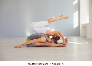 Yoga Couple Practice Acro Yoga On The Floor In A Studio Class.