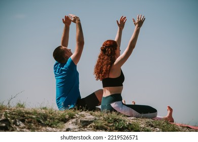 Yoga Couple Sitting At The Top Of The Mountain With Arms Up