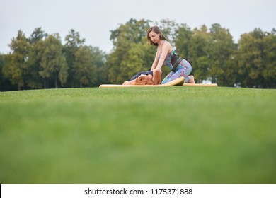 Yoga exercise on the lawn. Thai massage pose. Woman doing massage to woman.