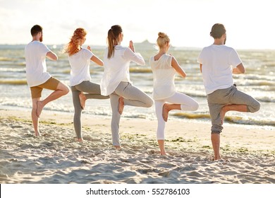 yoga, fitness, sport and healthy lifestyle concept - group of people in tree pose on beach - Powered by Shutterstock