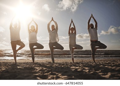 yoga, fitness, sport and healthy lifestyle concept - group of people in tree pose on beach - Powered by Shutterstock