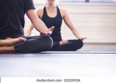 Yoga group concept. Young couple meditating together, sitting back to back on windows background, copy space - Shutterstock ID 552259924