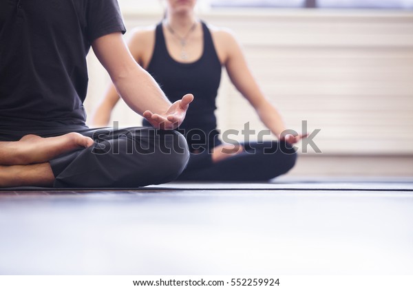 Yoga group\
concept. Young couple meditating together, sitting back to back on\
windows background, copy\
space