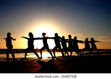 Yoga Group On The Beach As Silhouette At Sunset