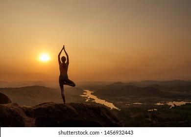 Yoga in Hampi temple copyspase at sunset.travel vacation copy spase lady with stylish jumpsuit