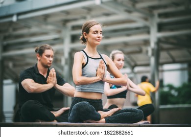  yoga and healthy lifestyle concept. group of sporty people practicing yoga lesson with instructor. yoga in the city
