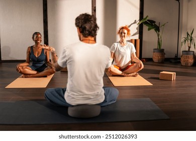 A yoga instructor guiding a student in a yoga studio with large windows and wooden floors. - Powered by Shutterstock