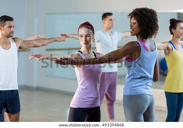 Yoga instructor helping student with a correct\
pose in fitness studio