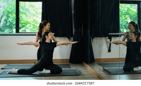 Yoga instructor helping student with posture alignment in fitness studio.