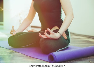 Yoga instructor in padmasana in yoga studio on the rug. Mat for yoga and a beautiful meditating woman. Morning meditation, yoga practice concept