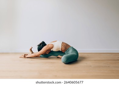 Yoga instructor practicing seated forward bend pose, demonstrating flexibility and mindfulness in a studio setting