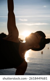Yoga instructor practicing a side plank variation at sunset on the beach
