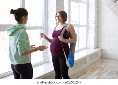 Yoga Instructor Talking To Pregnant Female Yoga Student