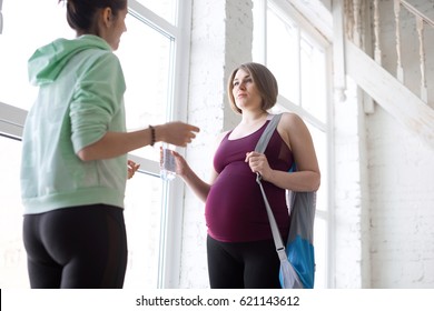 Yoga Instructor Talking To Pregnant Female Yoga Student