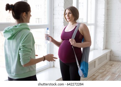 Yoga Instructor Talking To Pregnant Female Yoga Student