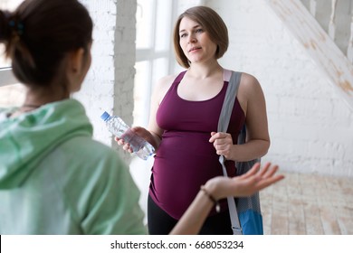 Yoga Instructor Talking To Pregnant Female Yoga Student