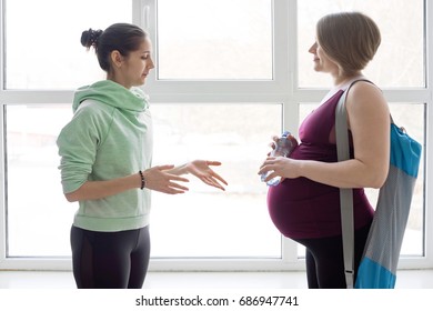 Yoga Instructor Talking To Pregnant Female Yoga Student